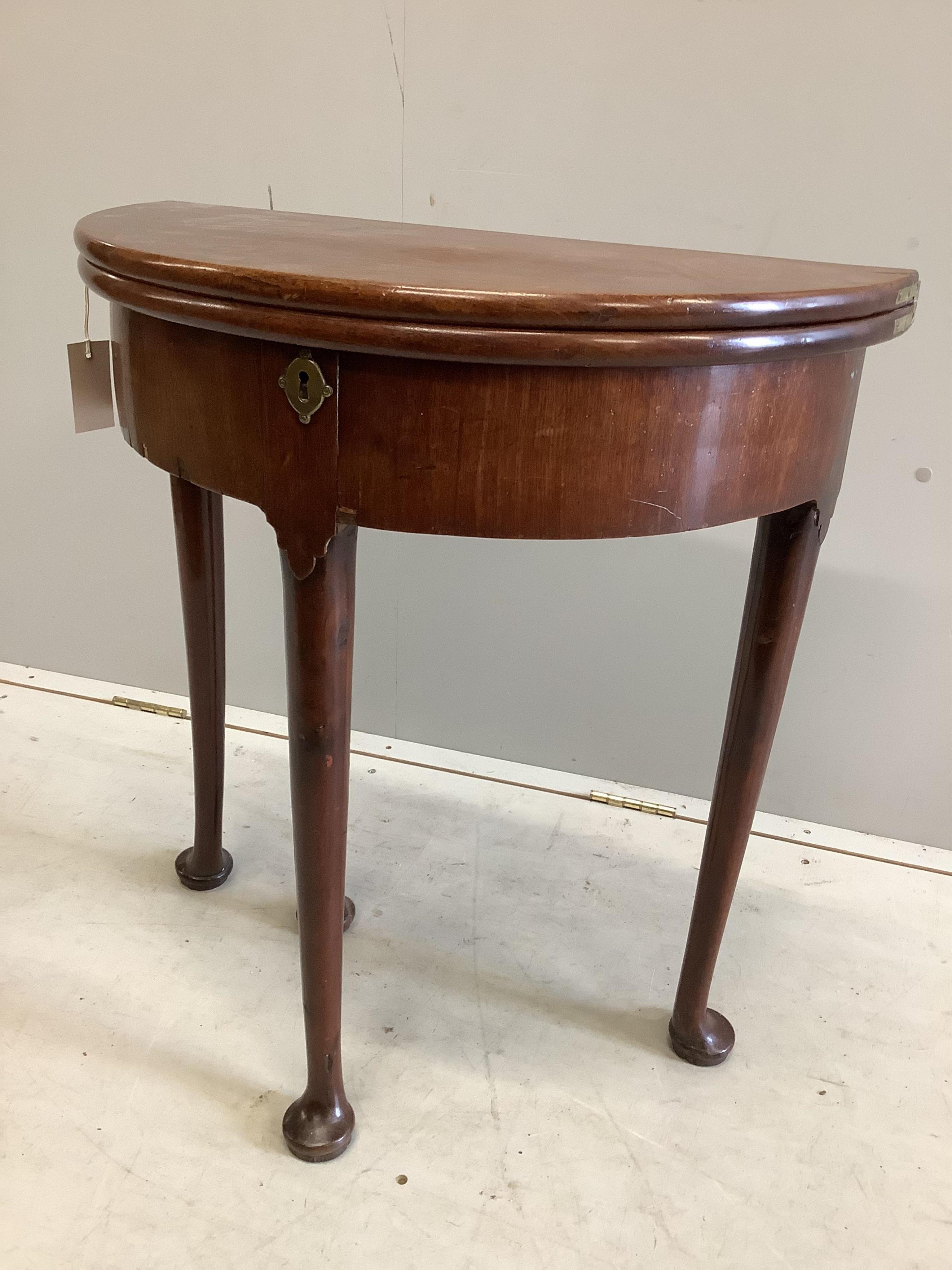 A small George II and later demi lune folding mahogany tea table, width 64cm, depth 32cm, height 70cm. Condition - fair